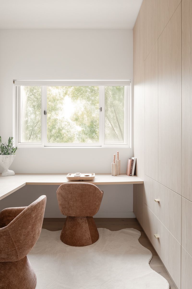 Desk nook with light wood cabinetry, window, and brown chairs on a rug. — SDC Building Design In Kiama, NSW
