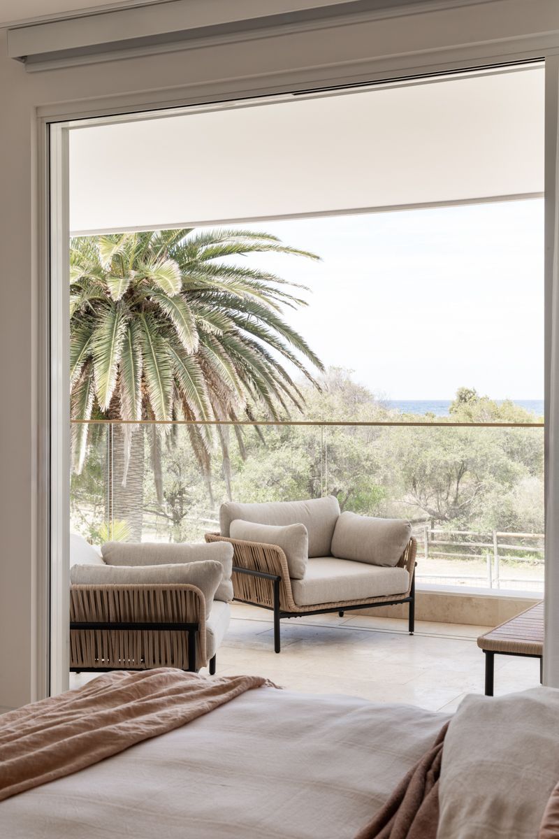 Bedroom with a balcony featuring outdoor furniture and a view of a palm tree and ocean — SDC Building Design In Wollongong, NSW