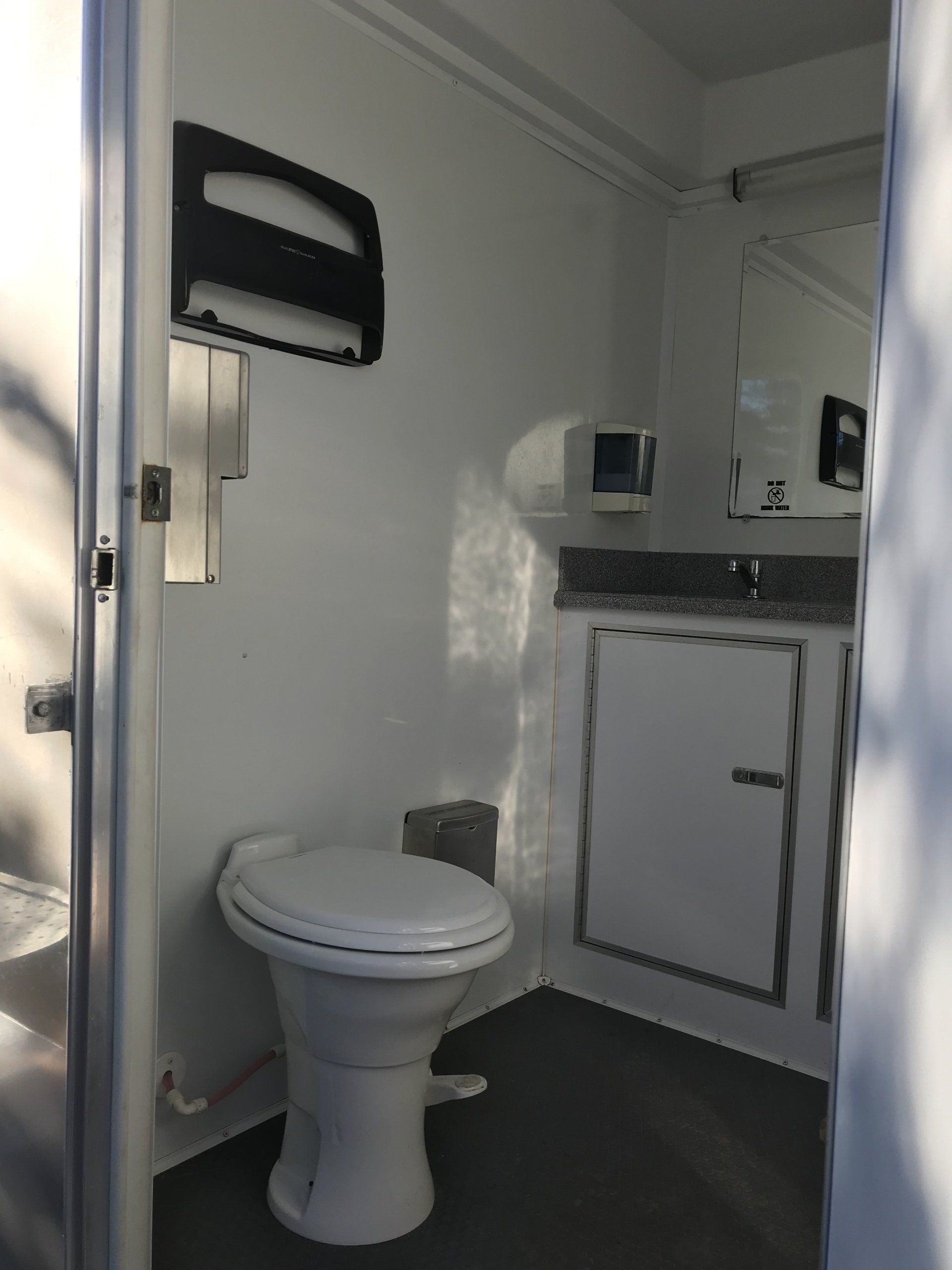 A bathroom with a toilet , sink and mirror.