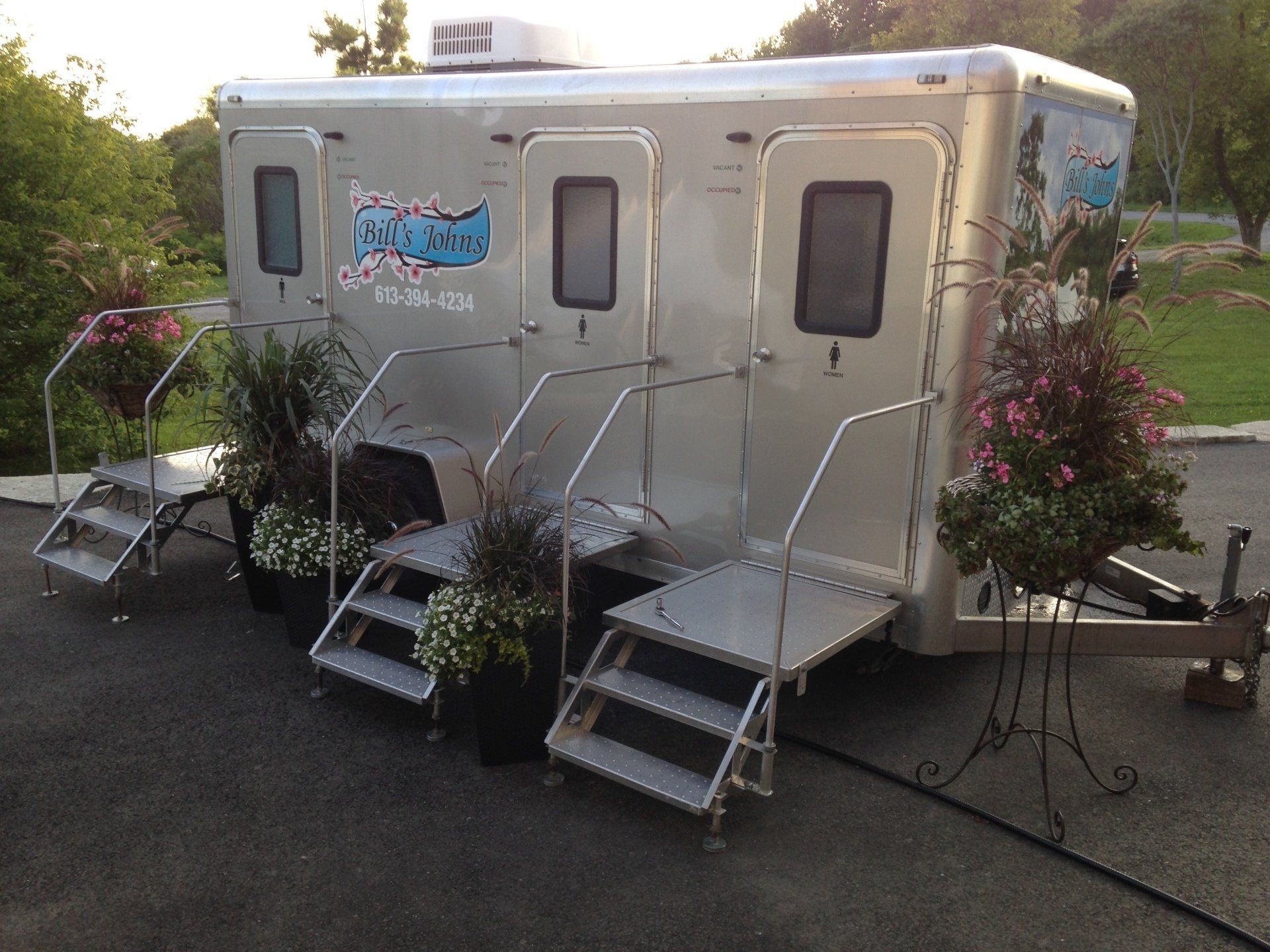 A trailer with stairs and flowers on it is parked in a parking lot.