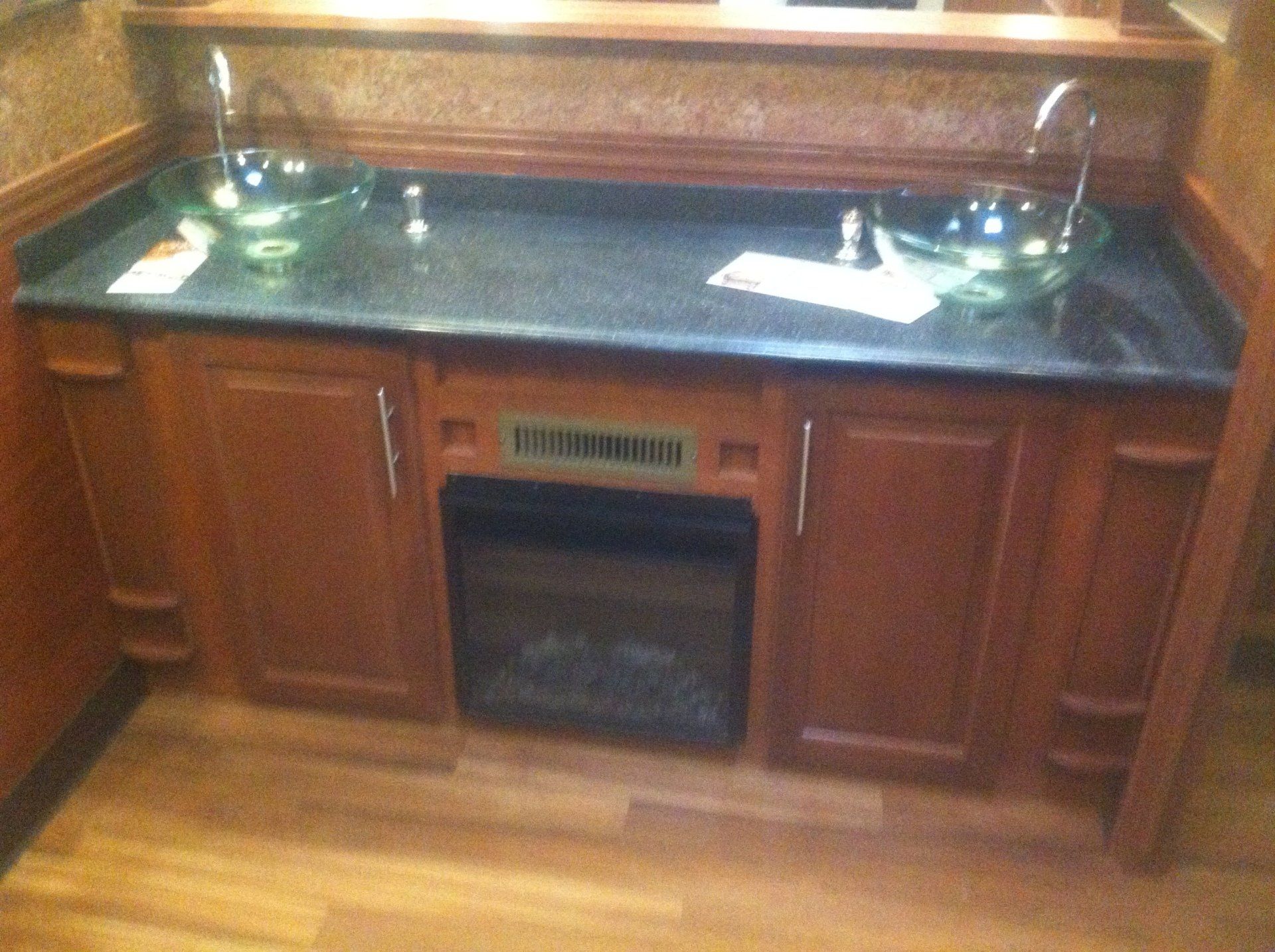 A kitchen counter with two sinks and a fireplace.