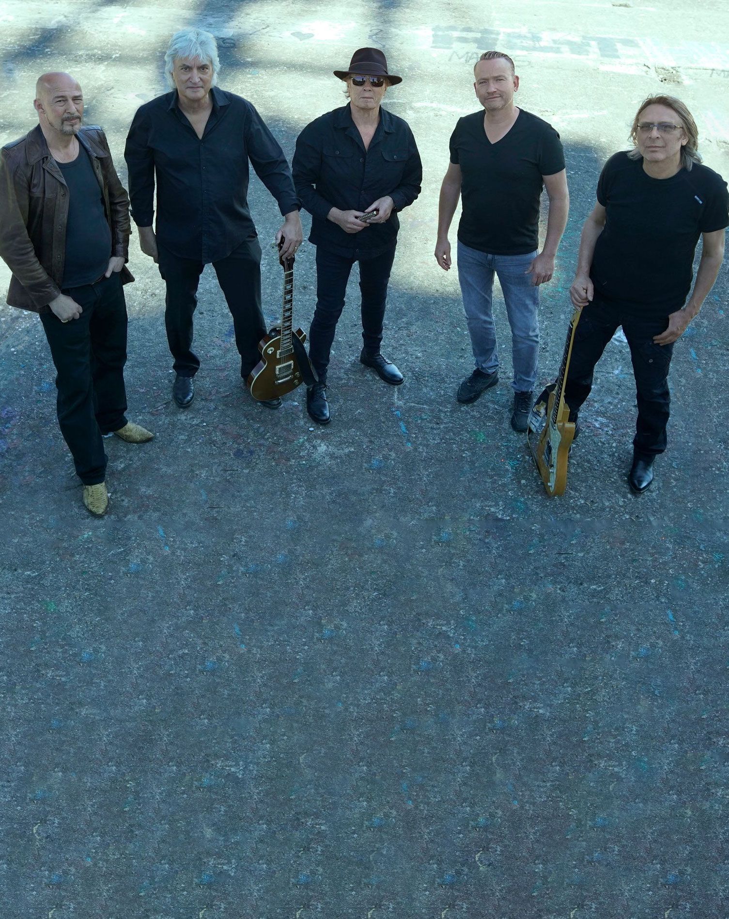 A group of men standing next to each other holding guitars and a saxophone.