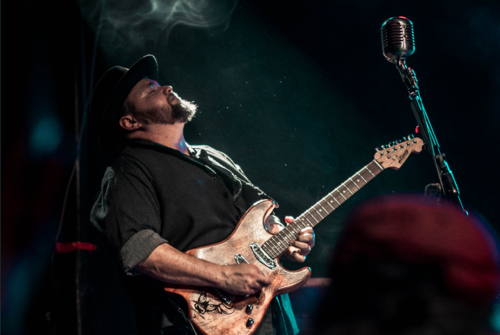 Hector Anchondo face looking up playing guitar on stage