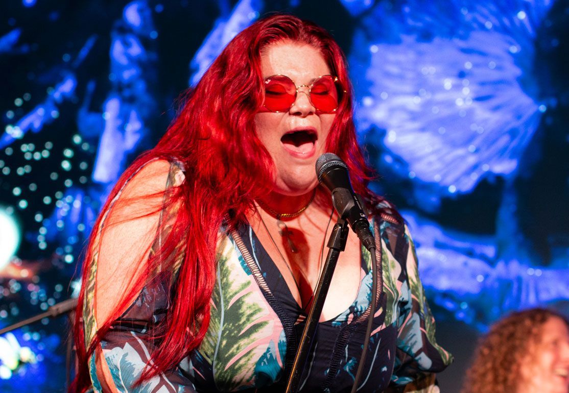 A woman with red hair is singing into a microphone.