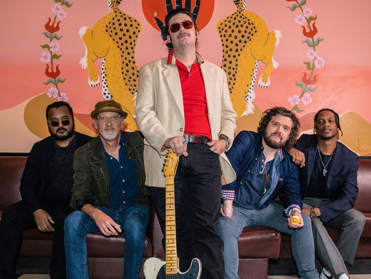 A group of men are posing for a picture with a man holding a guitar.