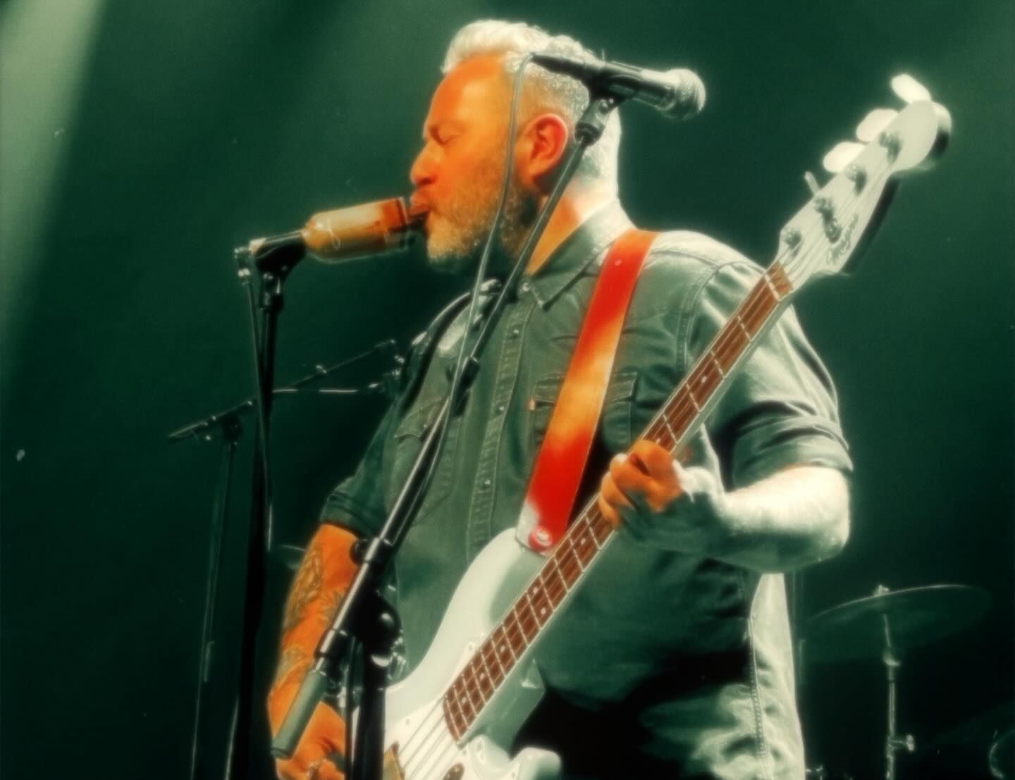 A man is playing a guitar on stage in front of a microphone.