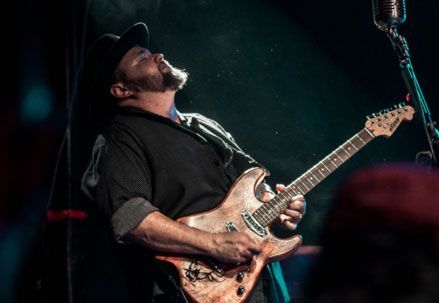 A man is playing a guitar on stage in front of a microphone.