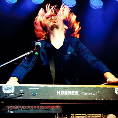 A man is and playing a Hohner keyboard