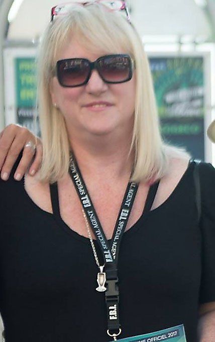 A blond woman wearing sunglasses and a lanyard
