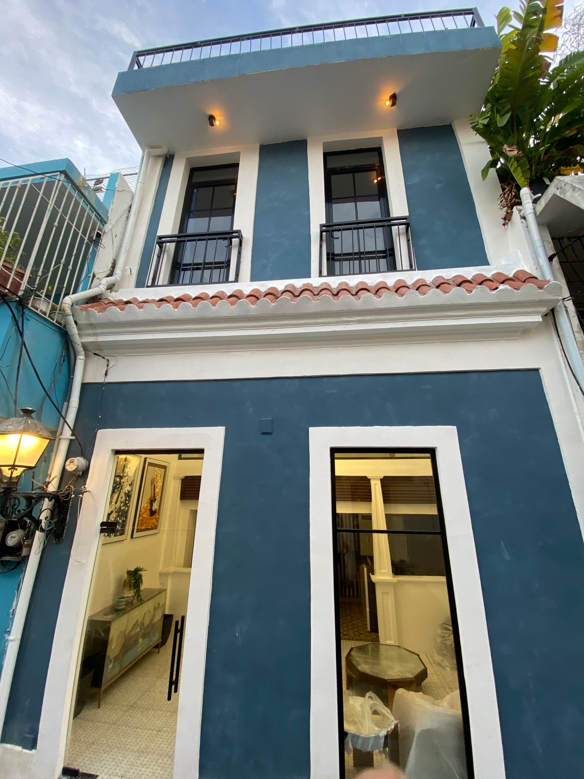Blue and white two-story building with balconies and large windows. Exterior lighting fixtures present.