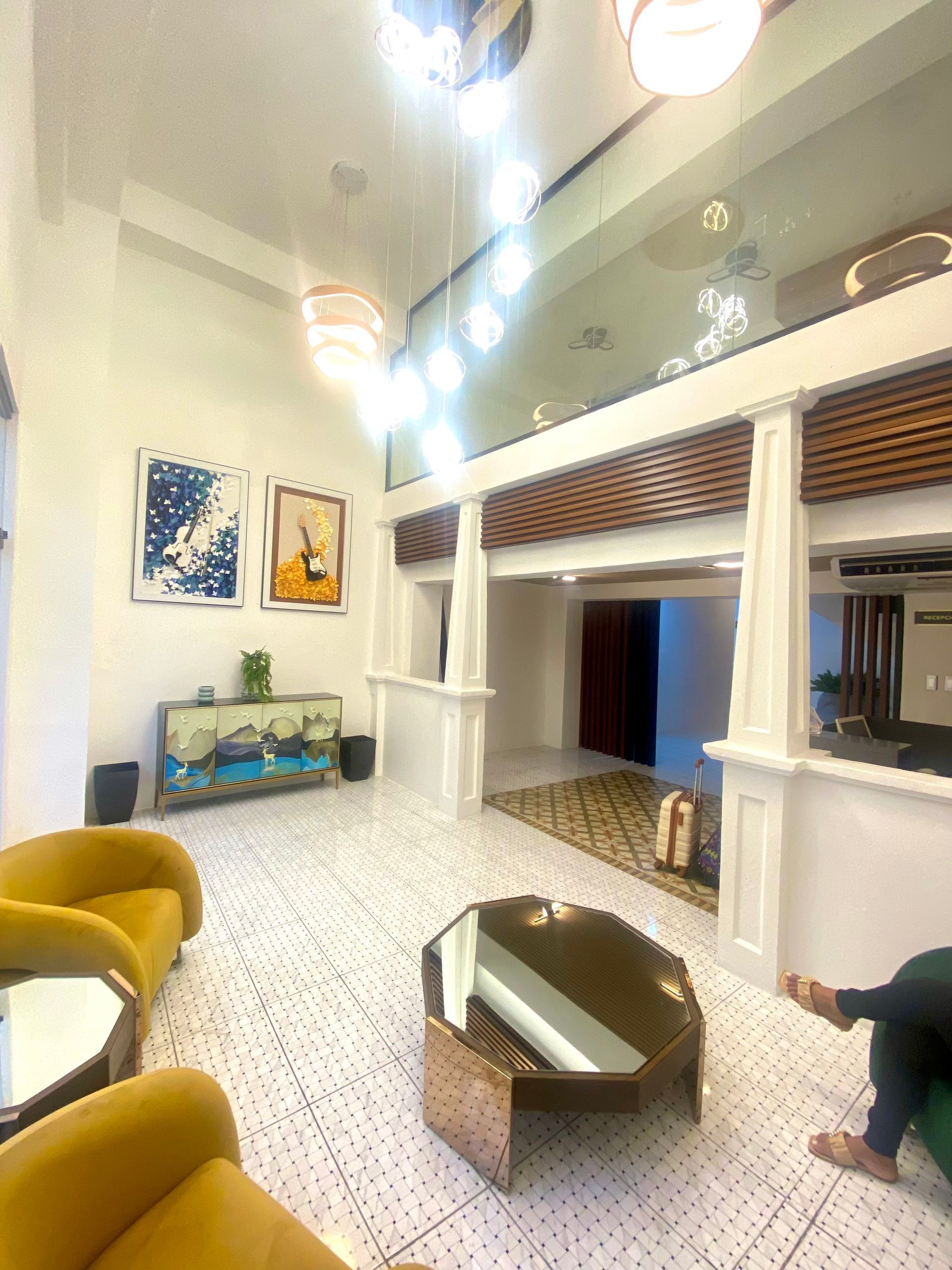 Bright lobby with gold furniture, white pillars, art, and patterned flooring.