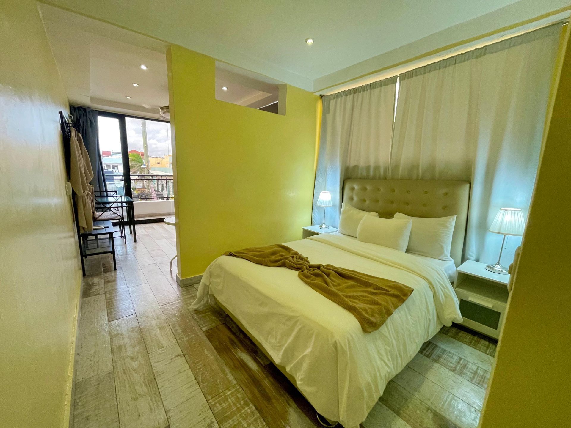 Bedroom with a bed, nightstands, and curtains, and a view into a dining area.