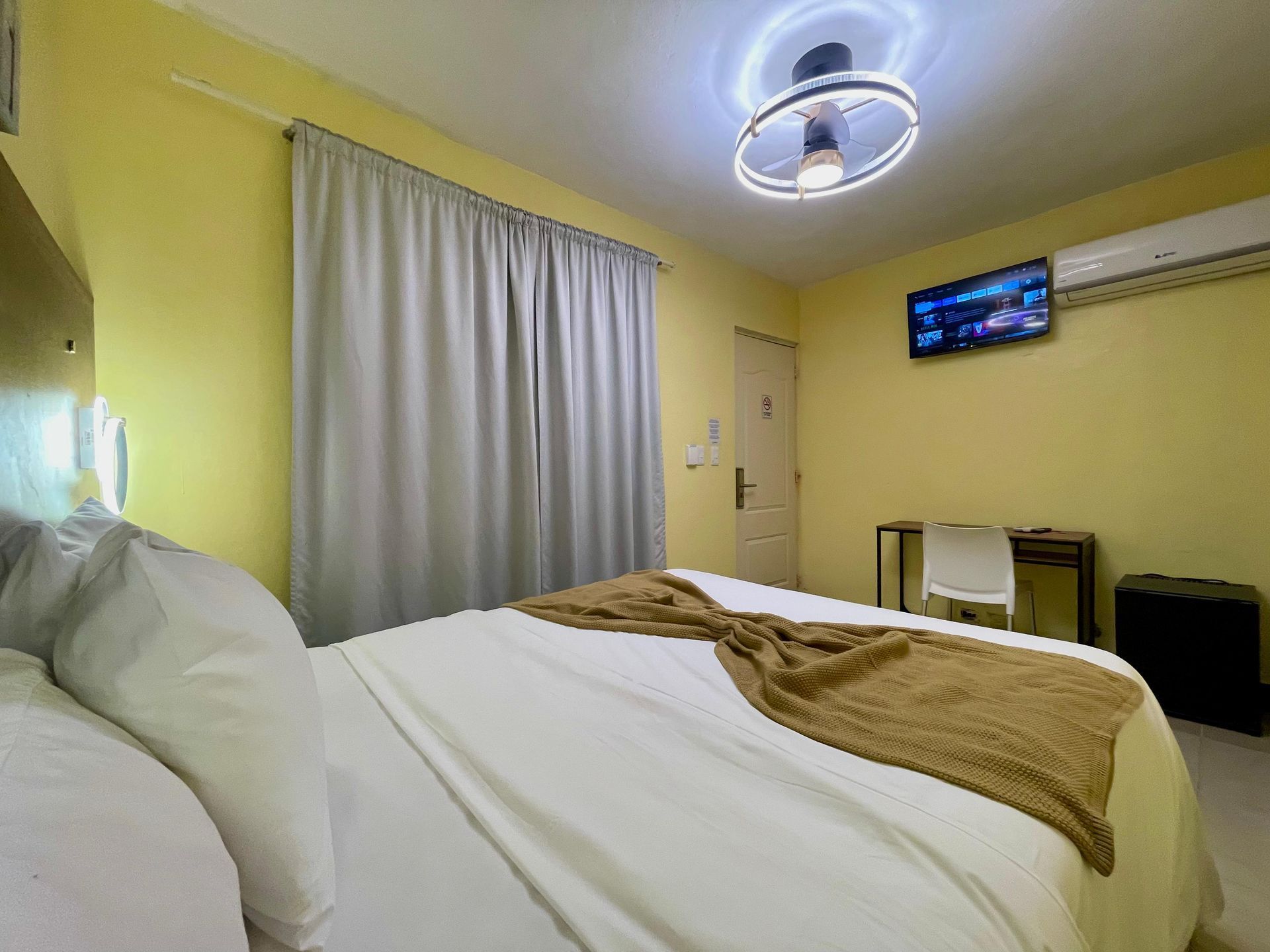 Bedroom with bed, yellow walls, and TV.