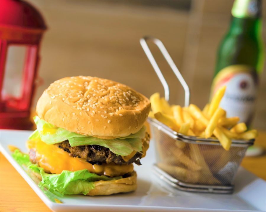 Hamburger with fries and a beer, on a white plate.