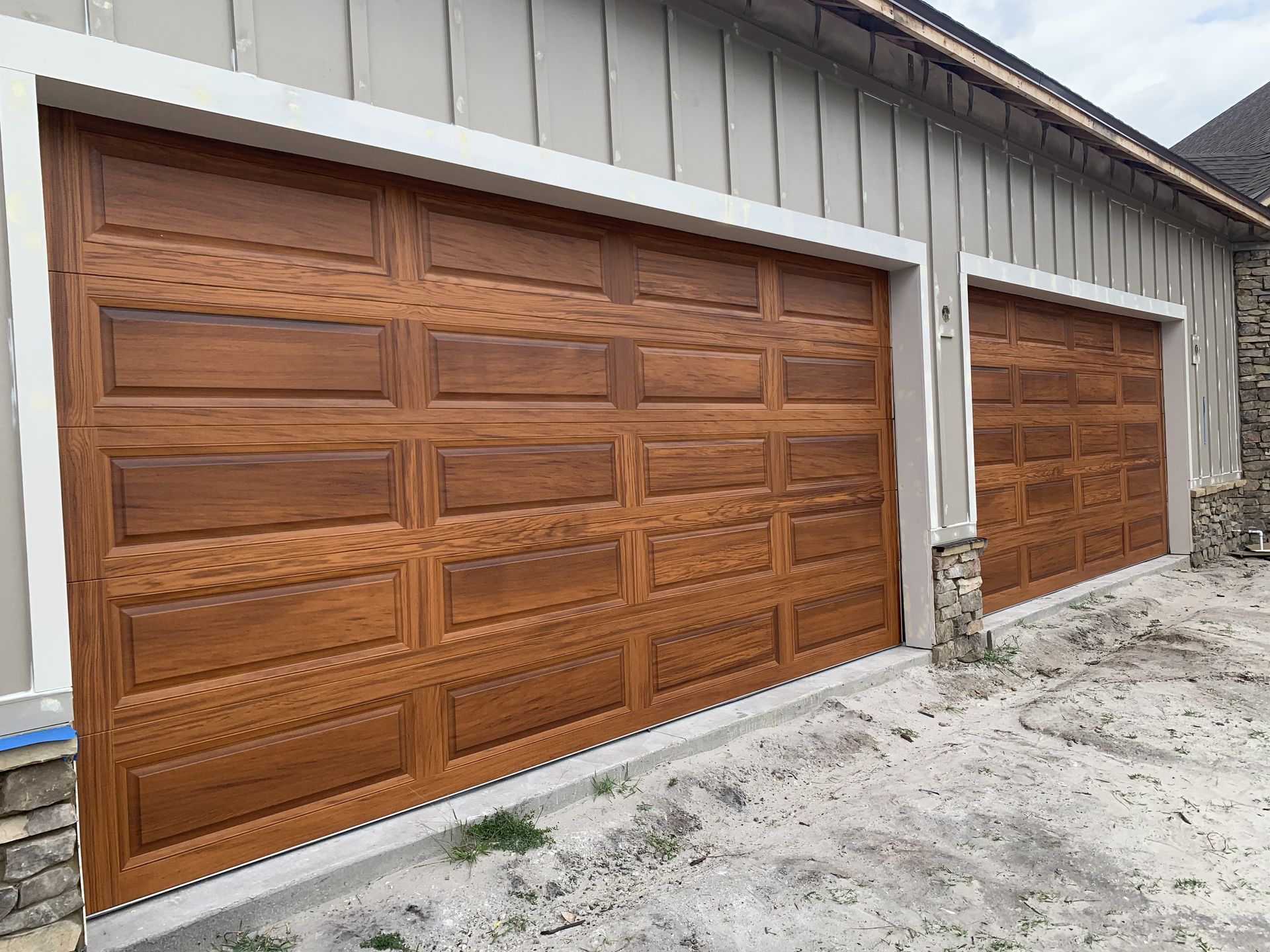 Three wooden garage doors are sitting on the side of a building.