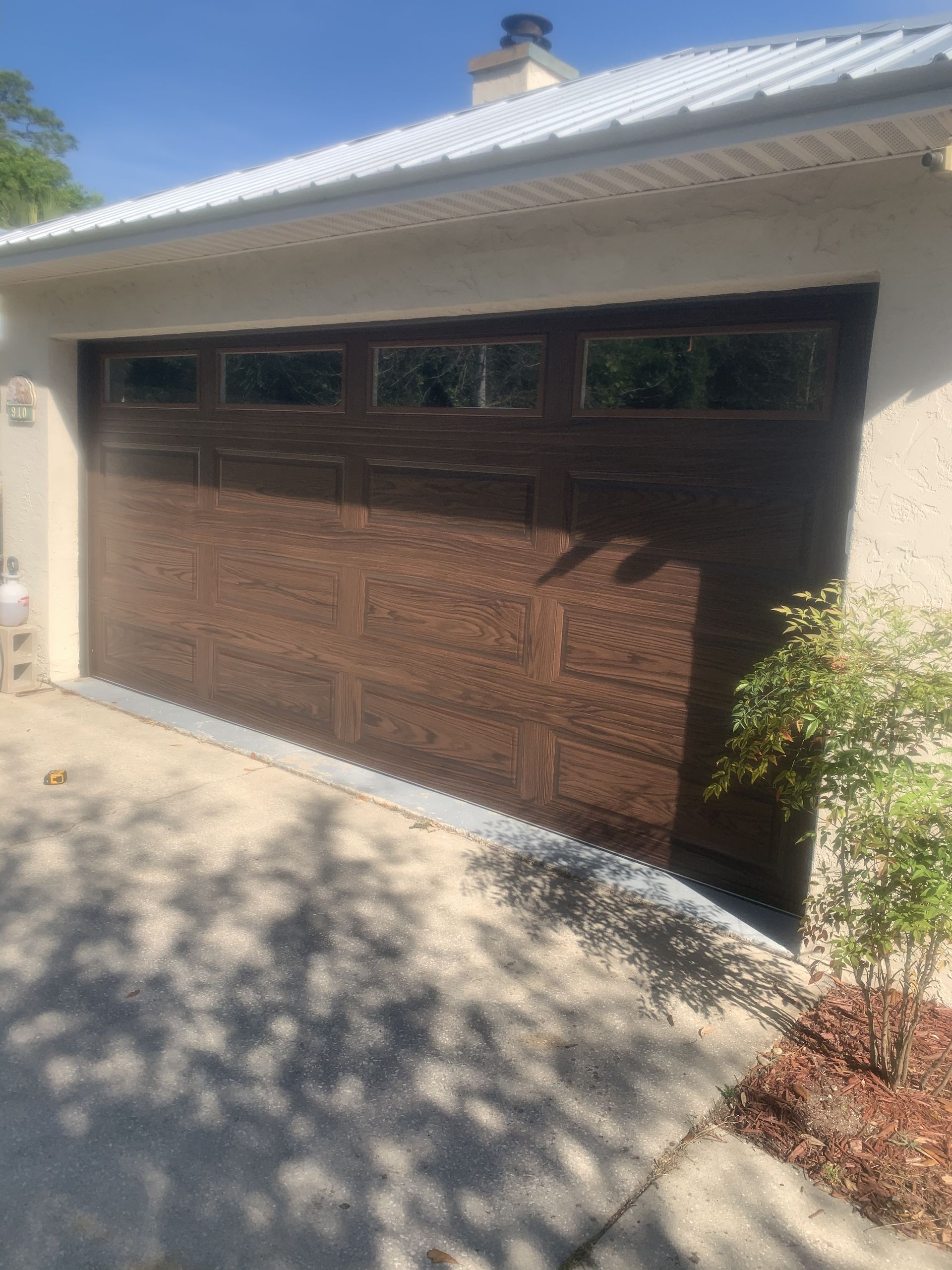 A brown garage door is sitting in front of a house.
