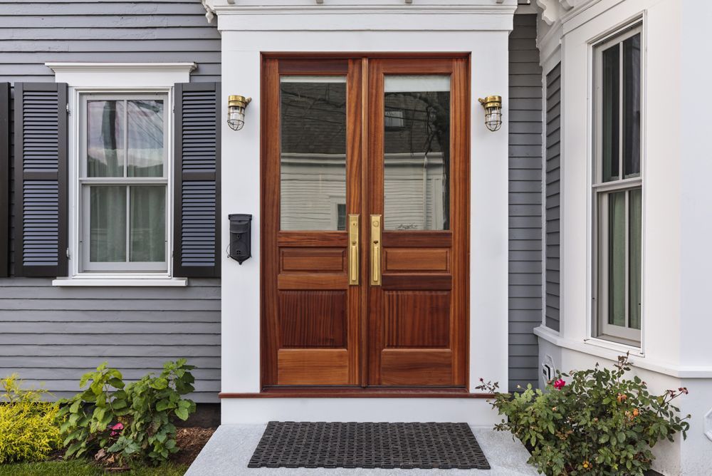 The front door of a house with a wooden door and shutters.