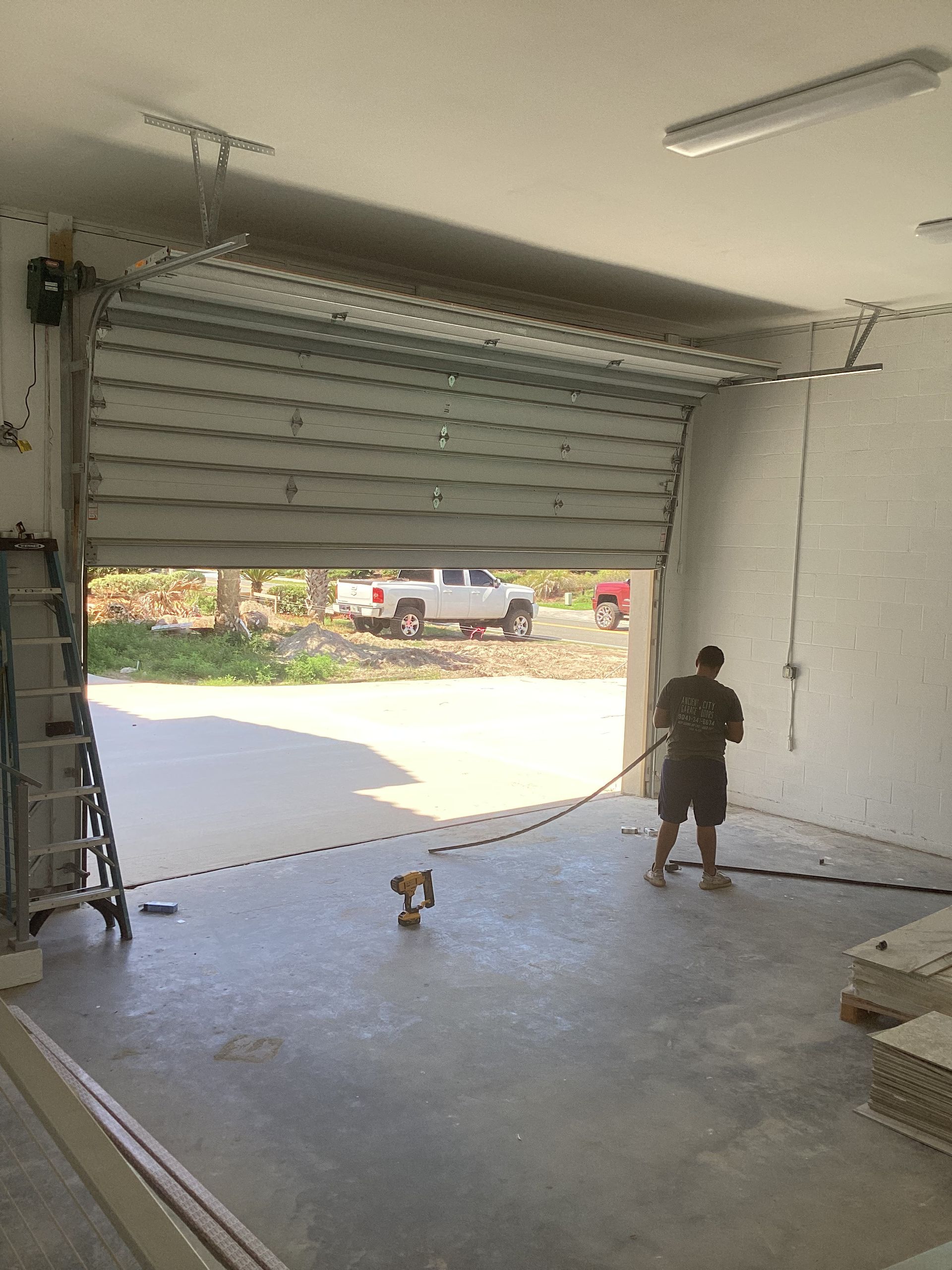 A man is standing in a garage with a garage door open.