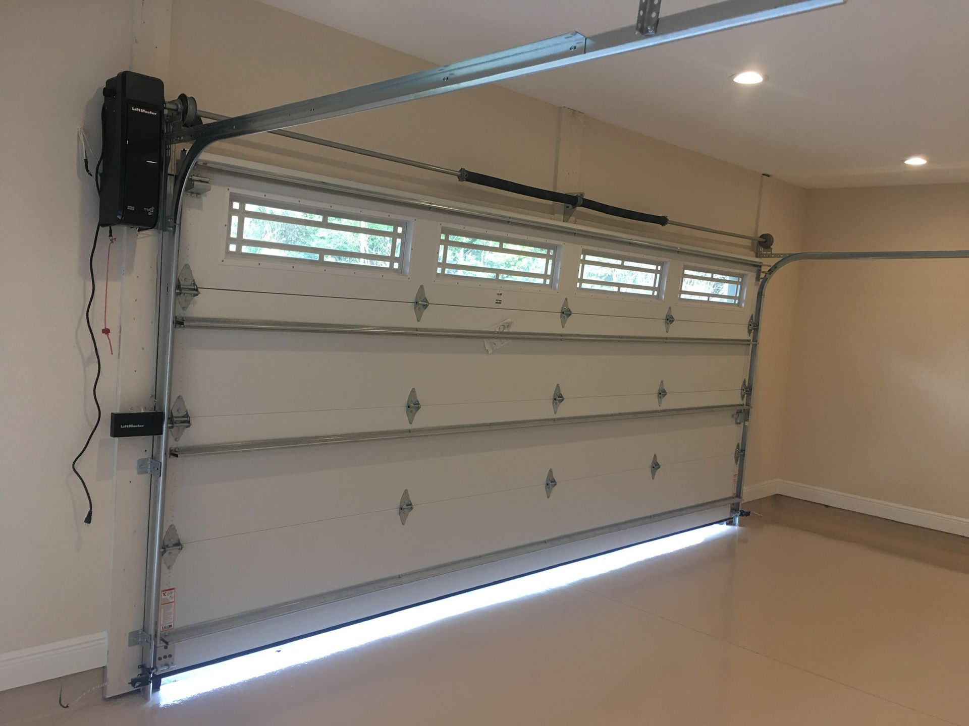 An empty garage with a garage door open and a garage door opener.