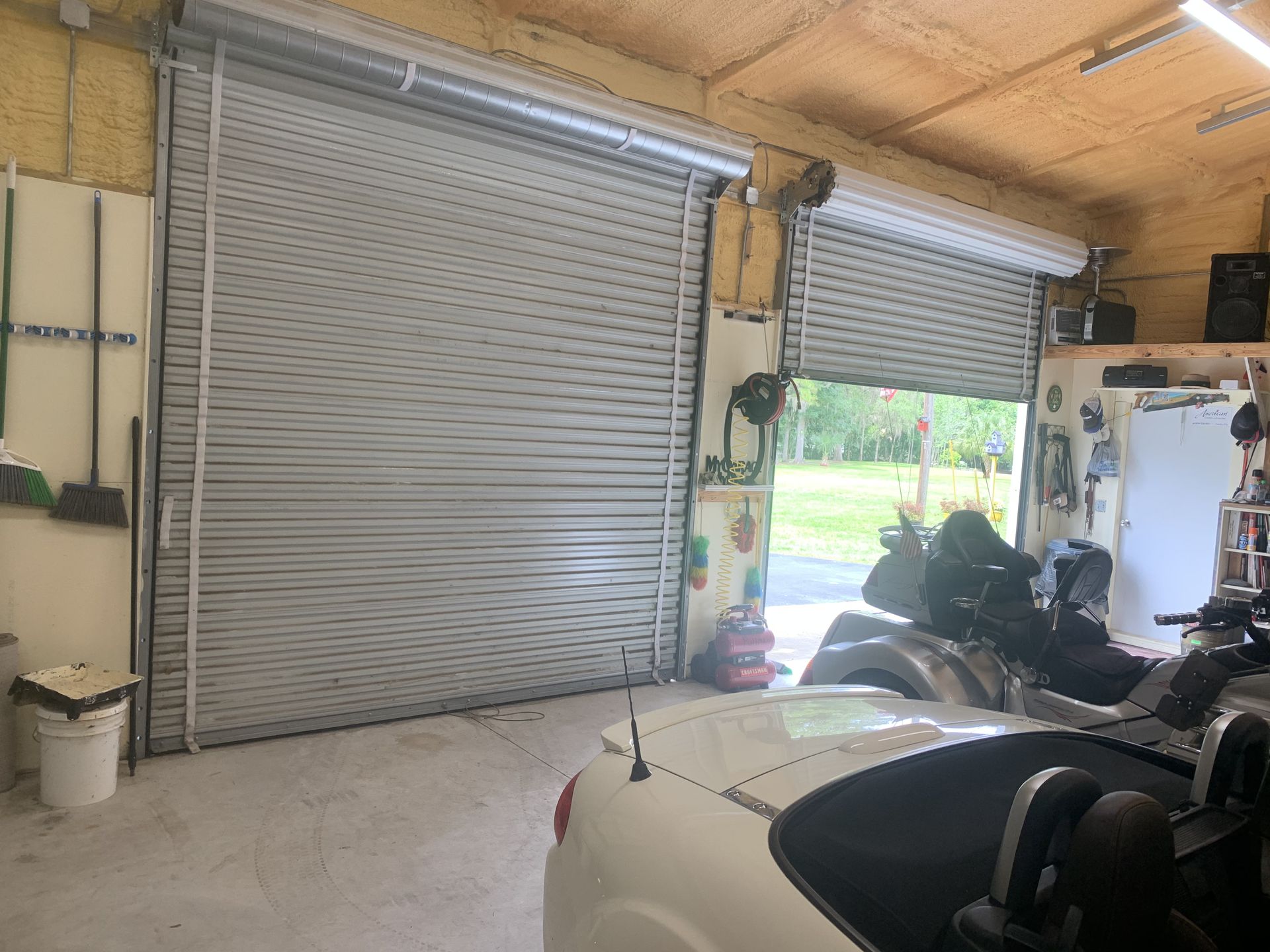 A white car is parked in a garage next to a motorcycle.