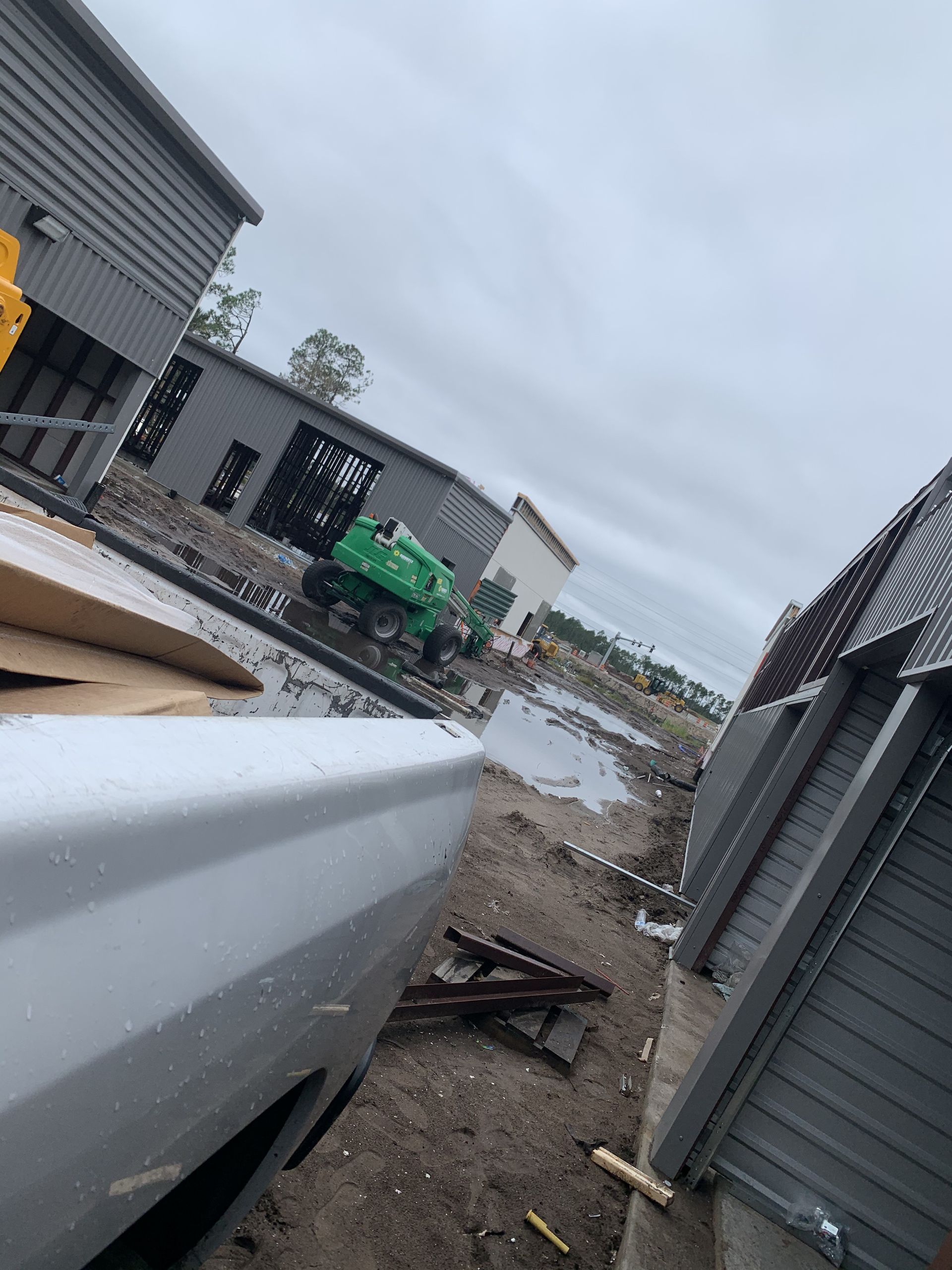 A white truck is parked in front of a building under construction.