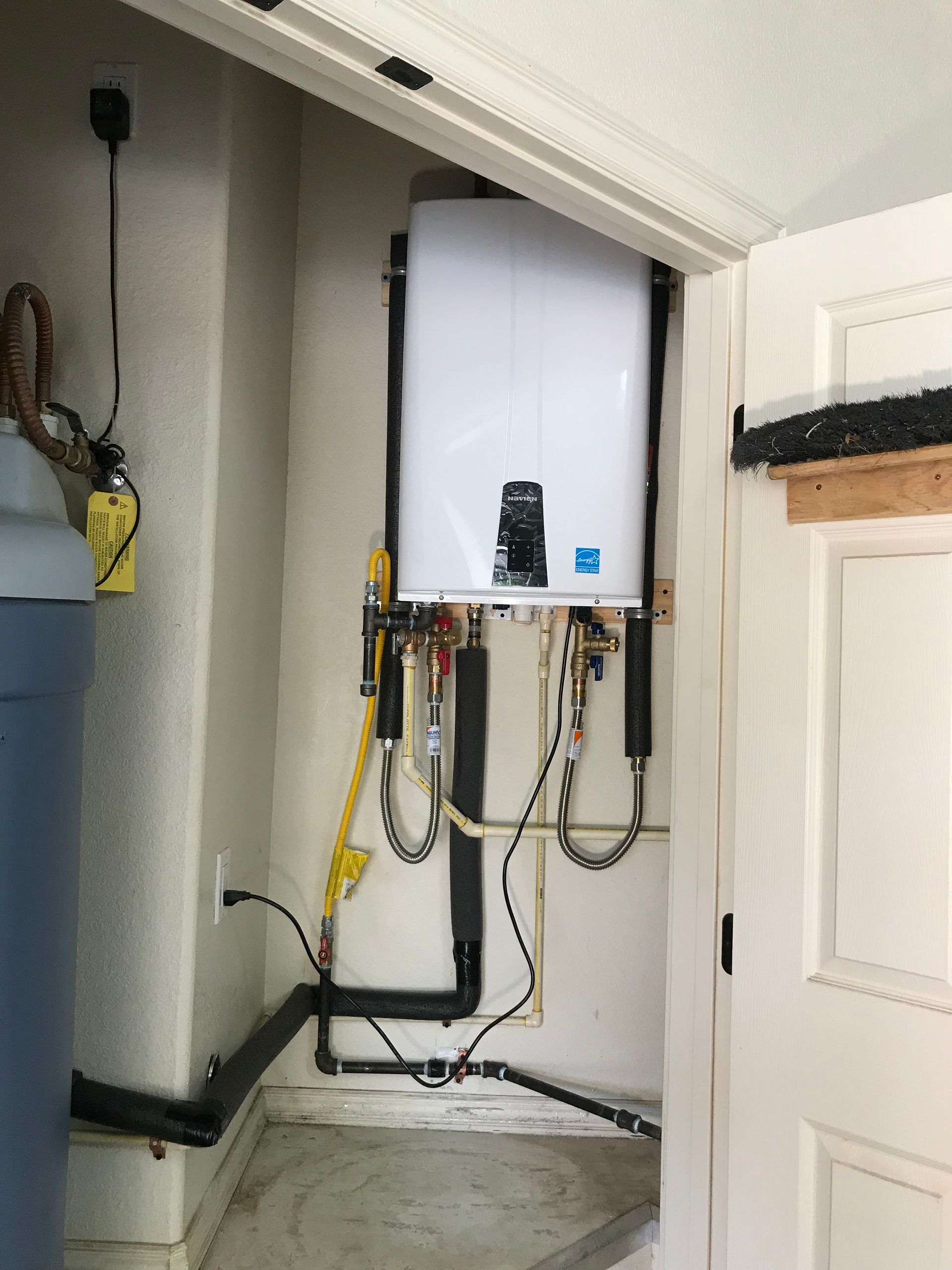 A water heater is mounted to the wall in a closet