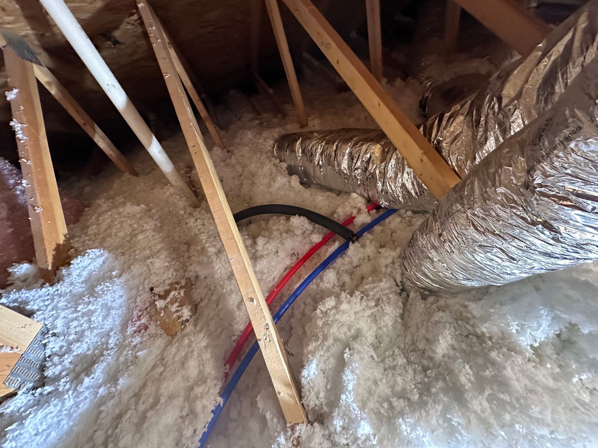 A bunch of wires are laying on the floor in an attic