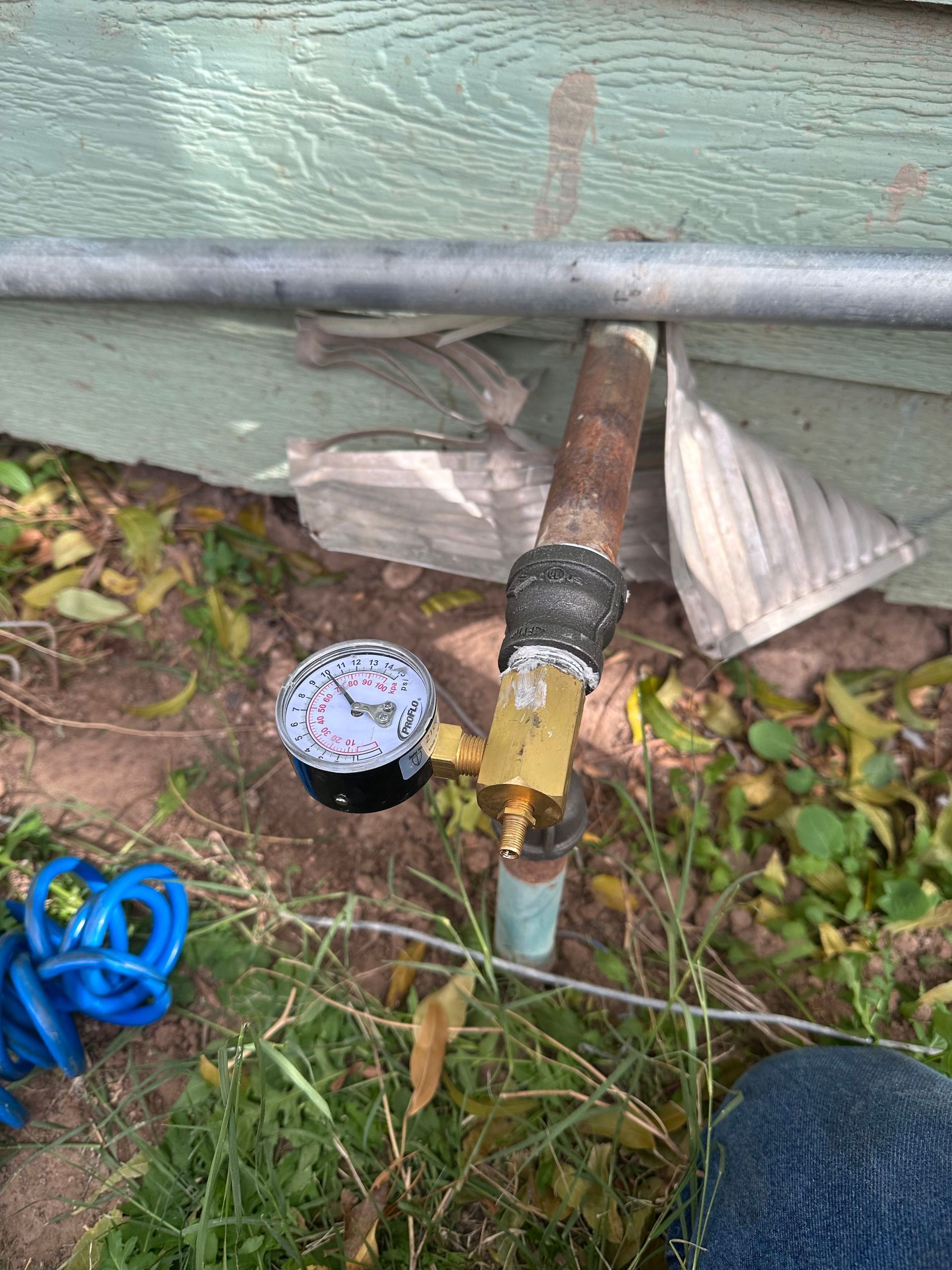 A pressure gauge is sitting on the ground next to a pipe.