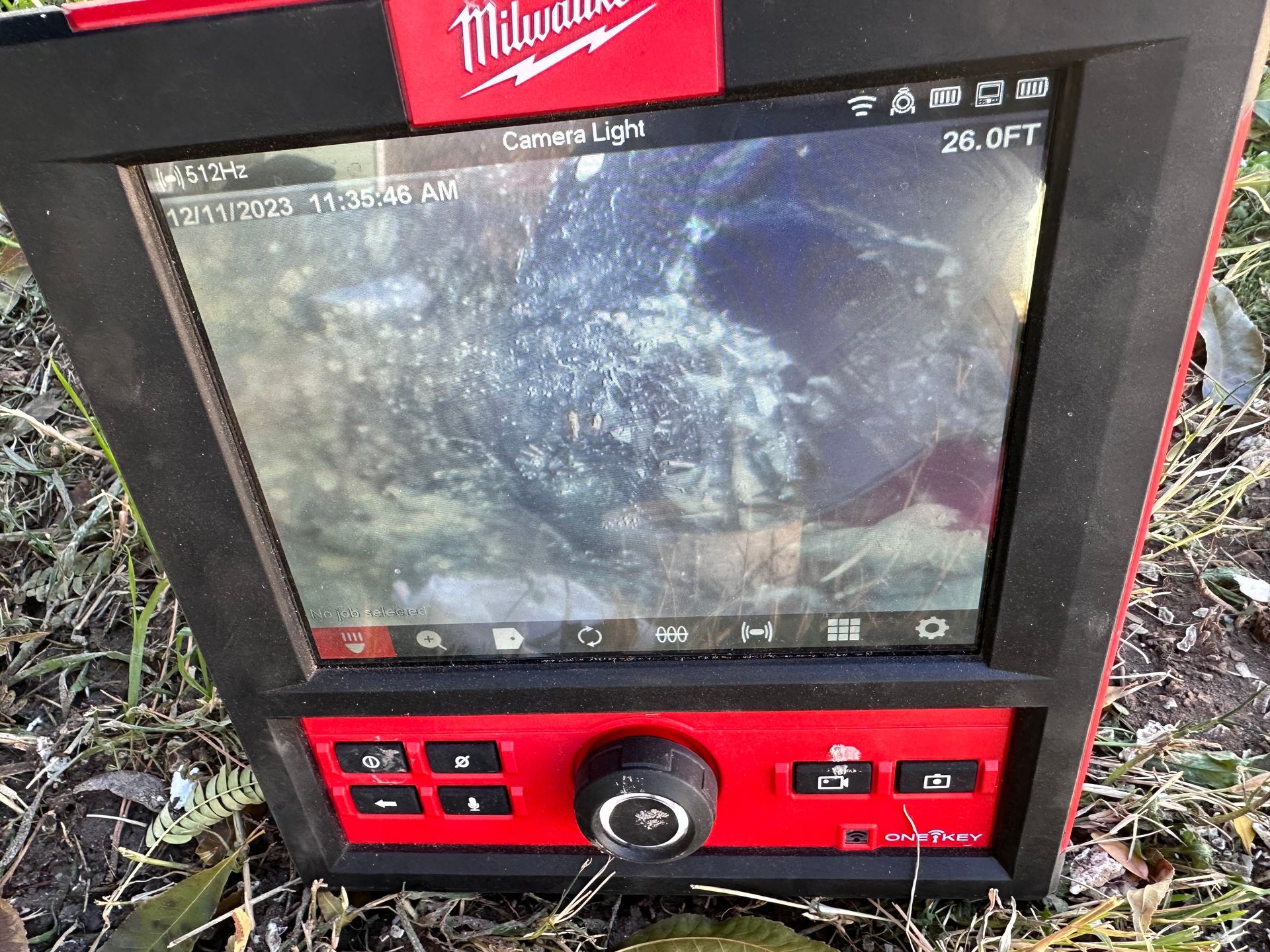 A red and black milwaukee device is sitting in the grass