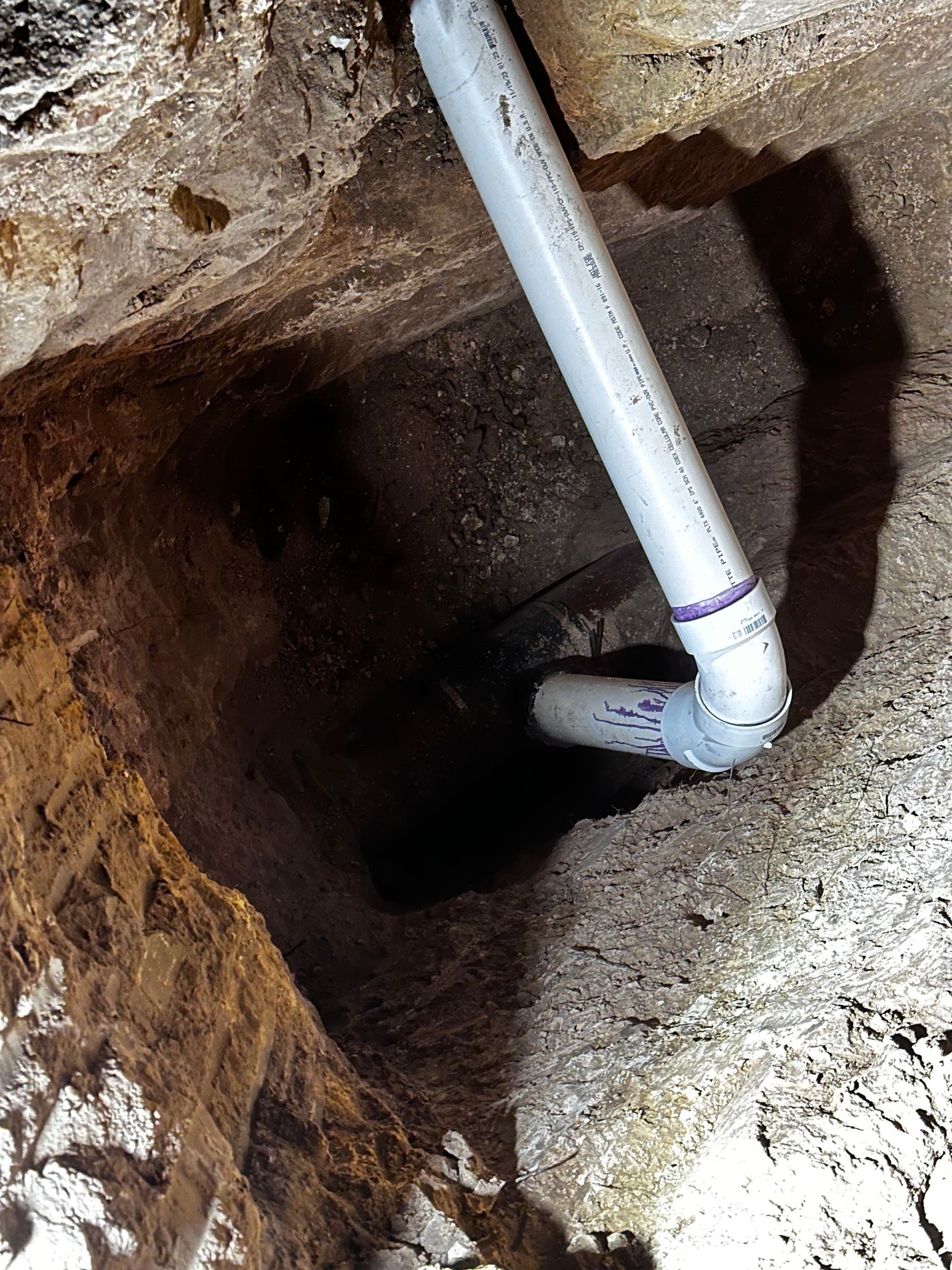A white pipe is coming out of a hole in the ground