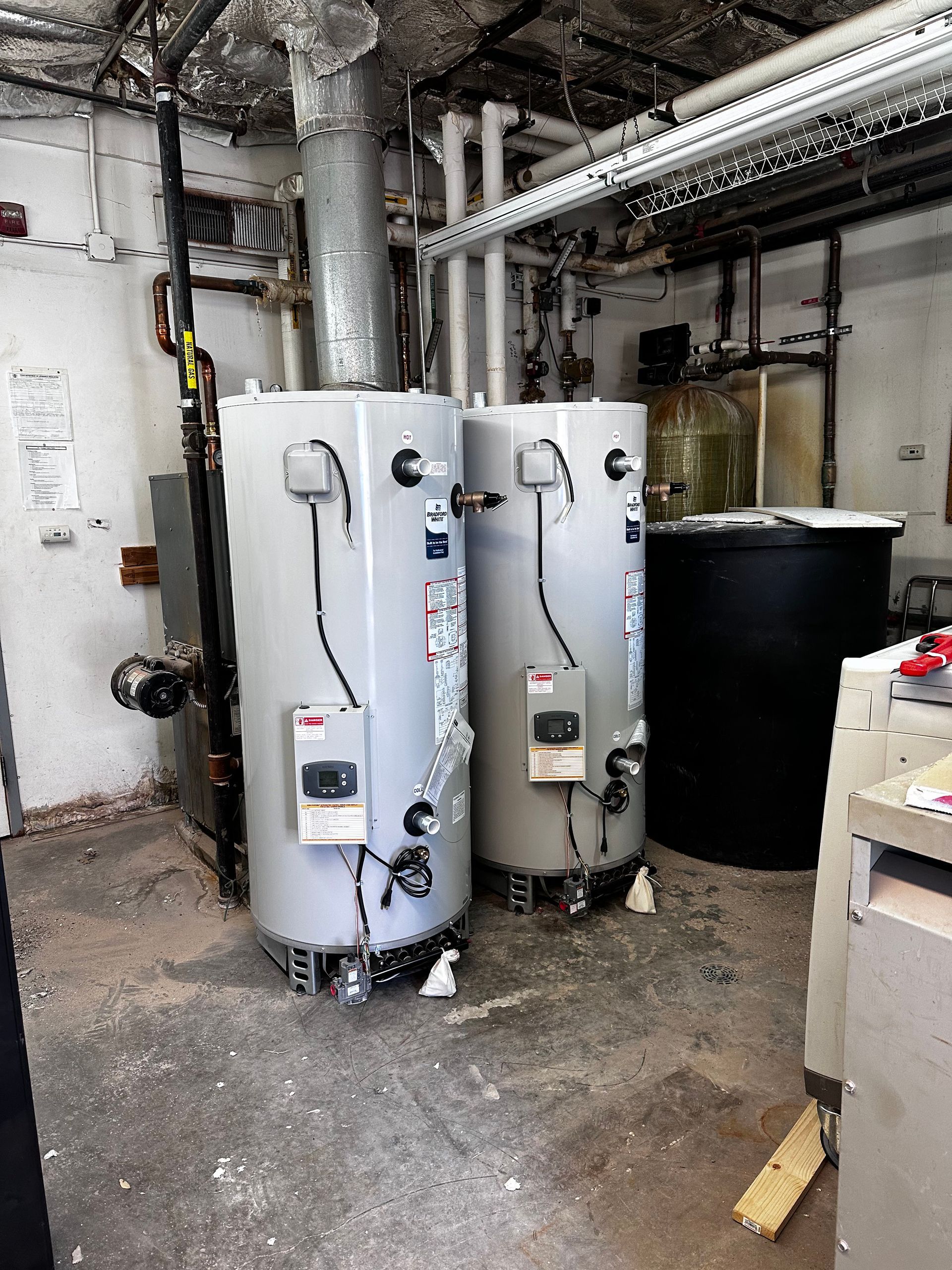 Two water heaters are sitting in a dirty room