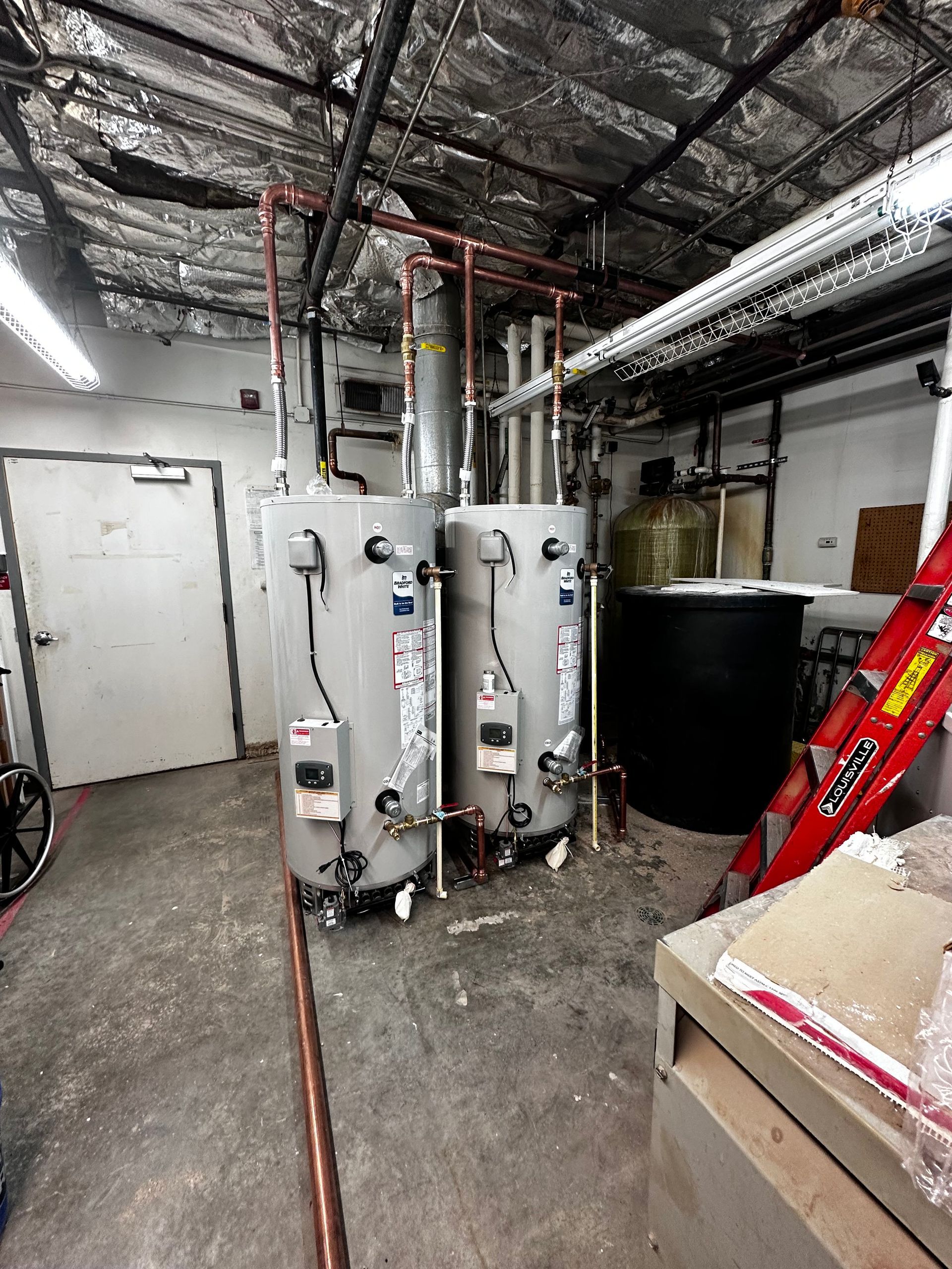A room with two water heaters and a ladder