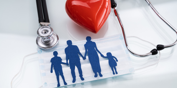 Health insurance concept with stethoscope, heart, and family cutout figures on medical documents
