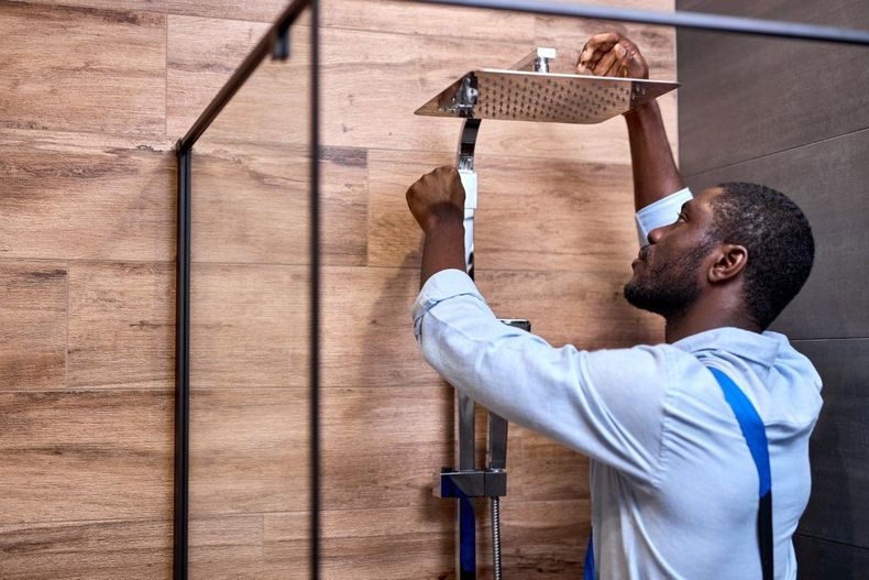 Worker installing a wall-mounted shelf with a drill in a wood-paneled room