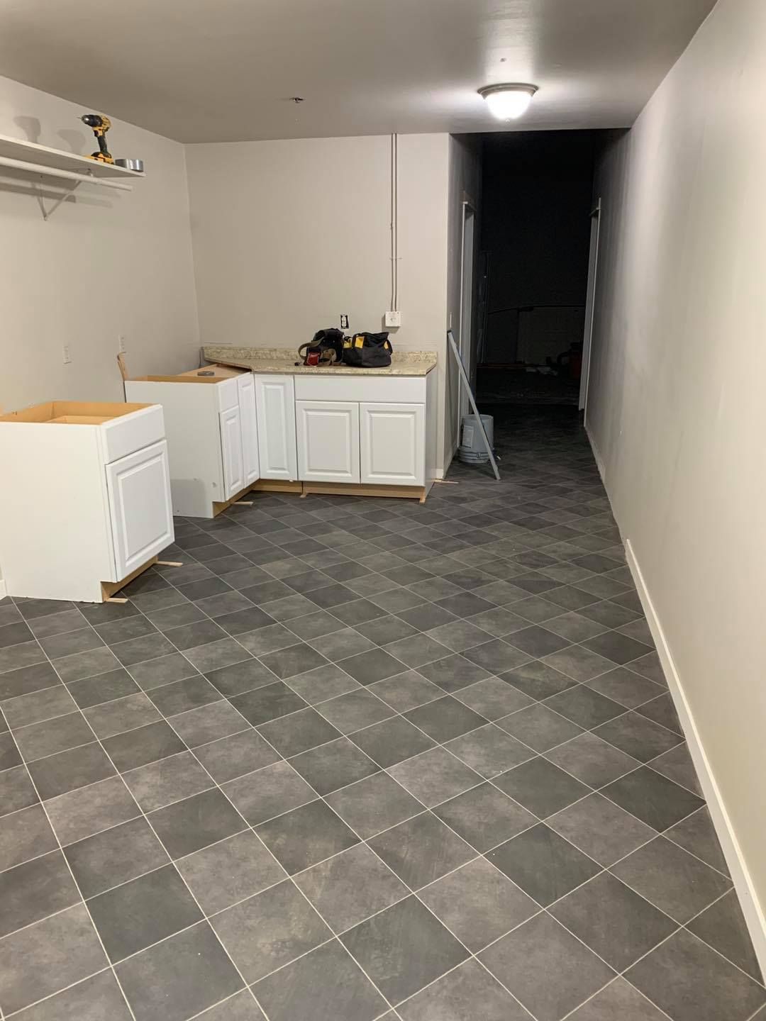 Kitchen with white cabinets, gray tile floor, and unfinished countertops.