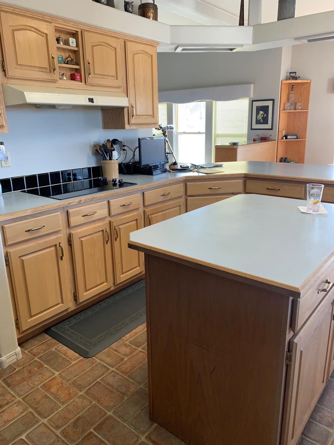 Kitchen with light wood cabinets, tiled floor, and a dark brown island.