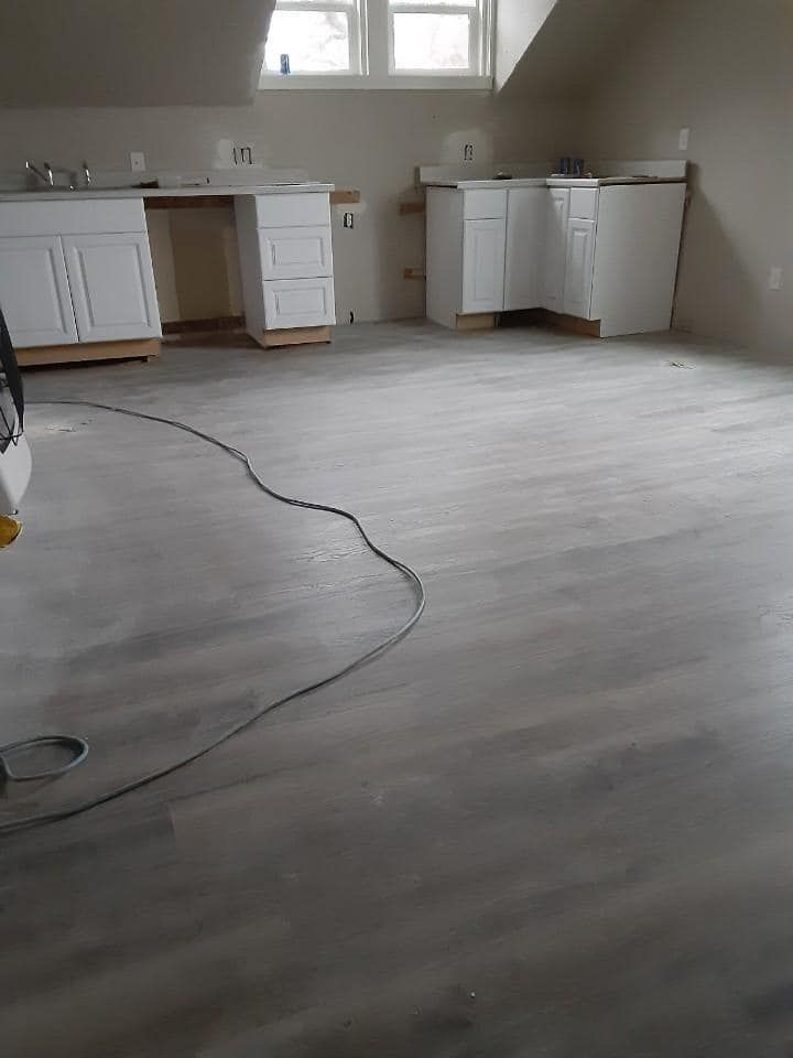 New construction interior with white cabinets and gray flooring, awaiting fixtures.