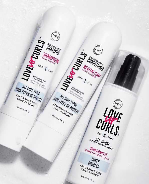 Three white Love My Curls hair product bottles. Shampoo, conditioner, and all-in-one serum.