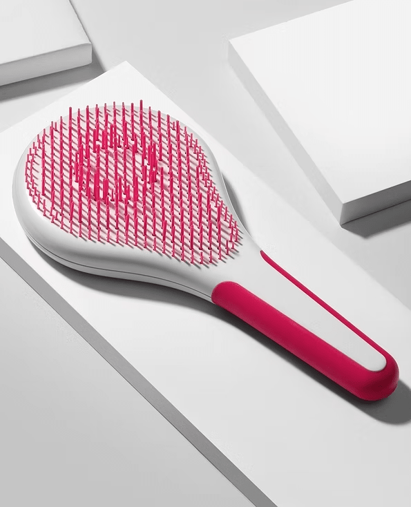 White and pink hairbrush on white geometric background.