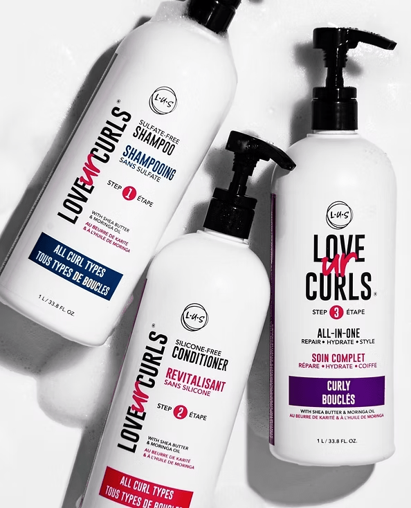 Three white Love Ur Curls hair product bottles: shampoo, conditioner, and all-in-one, on a white surface.