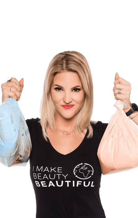 Woman holding blue and pink trash bags, wearing a “I make beauty beautiful” shirt, looking at camera.