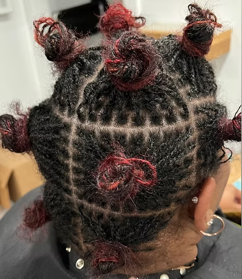Close-up of hair styled in square sections with red-dyed Bantu knots.