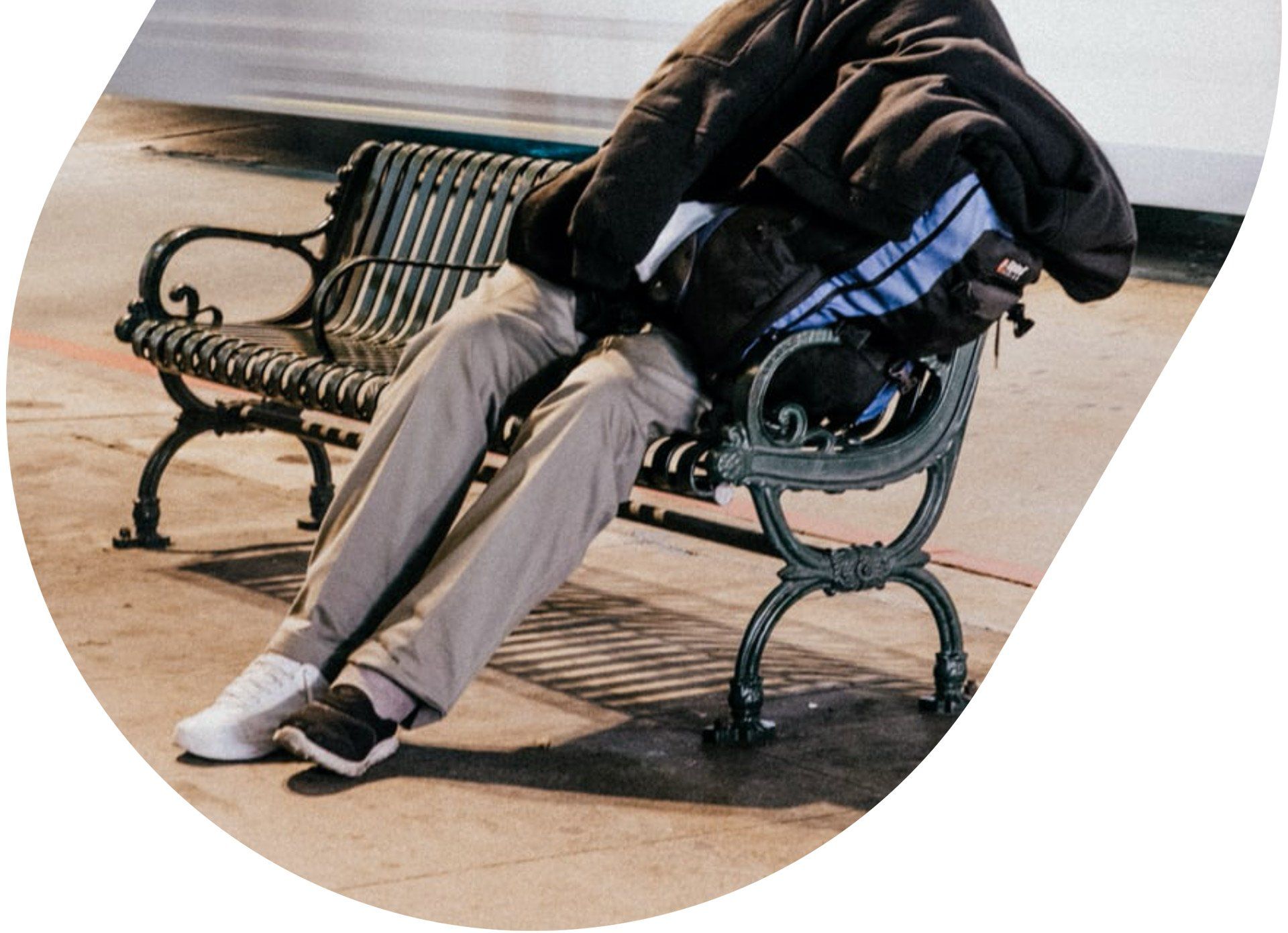 homeless man on a street bench with mismatched shoes