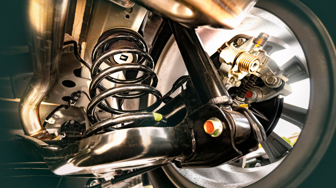 A close up of the underside of a car with a shock absorber and a wheel.