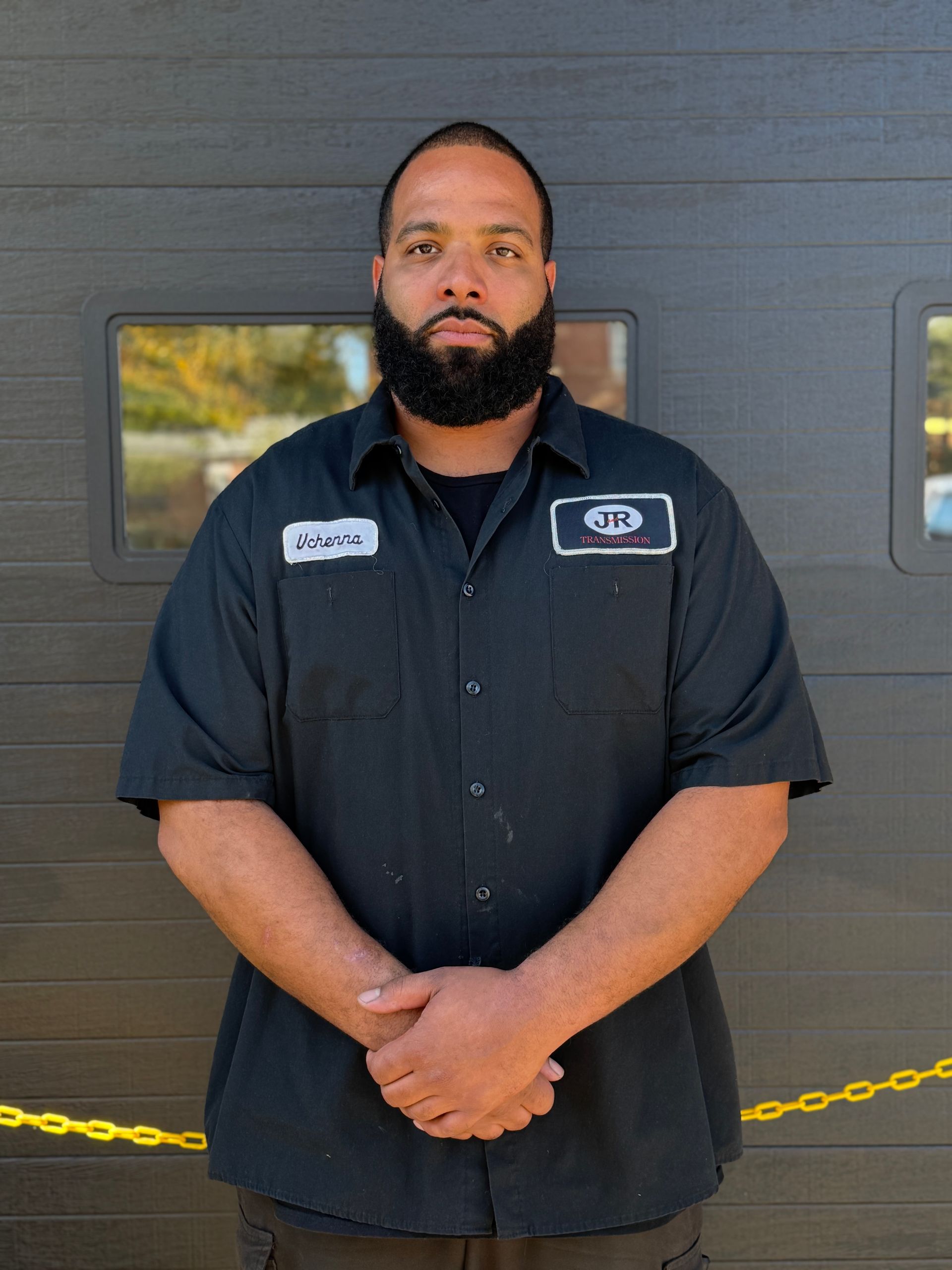 A man with a beard is standing in front of a truck.