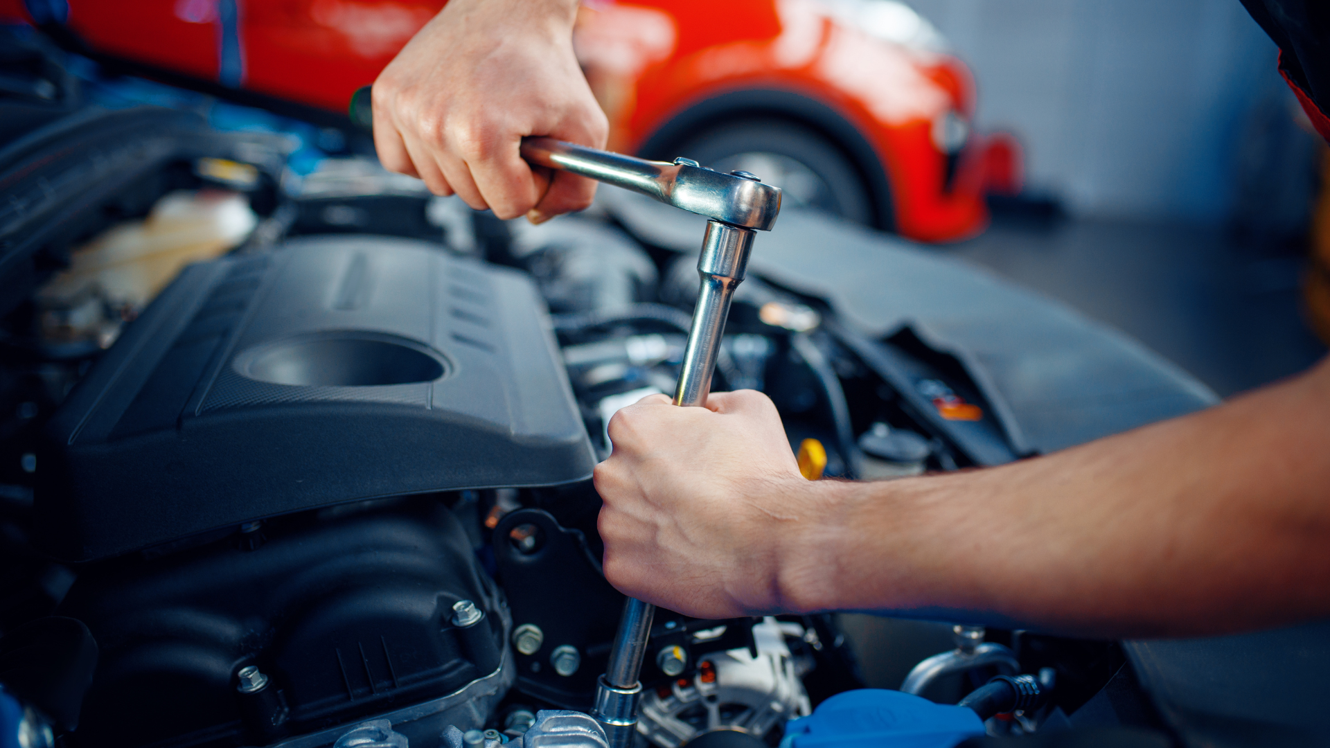 A man is working on a car engine with a wrench.