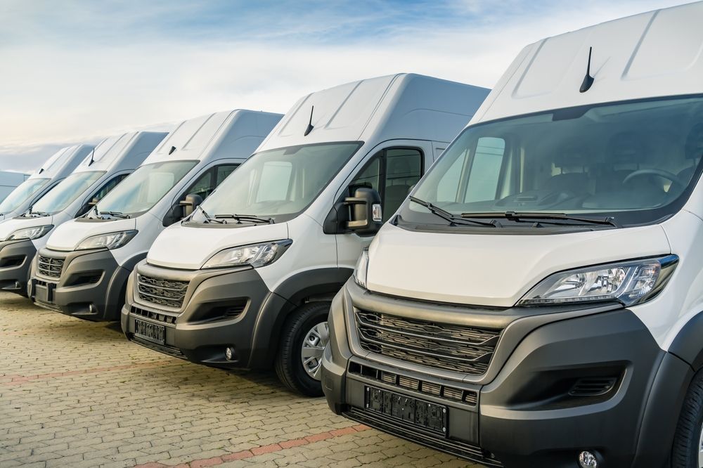 Row of white delivery vans parked outdoors.