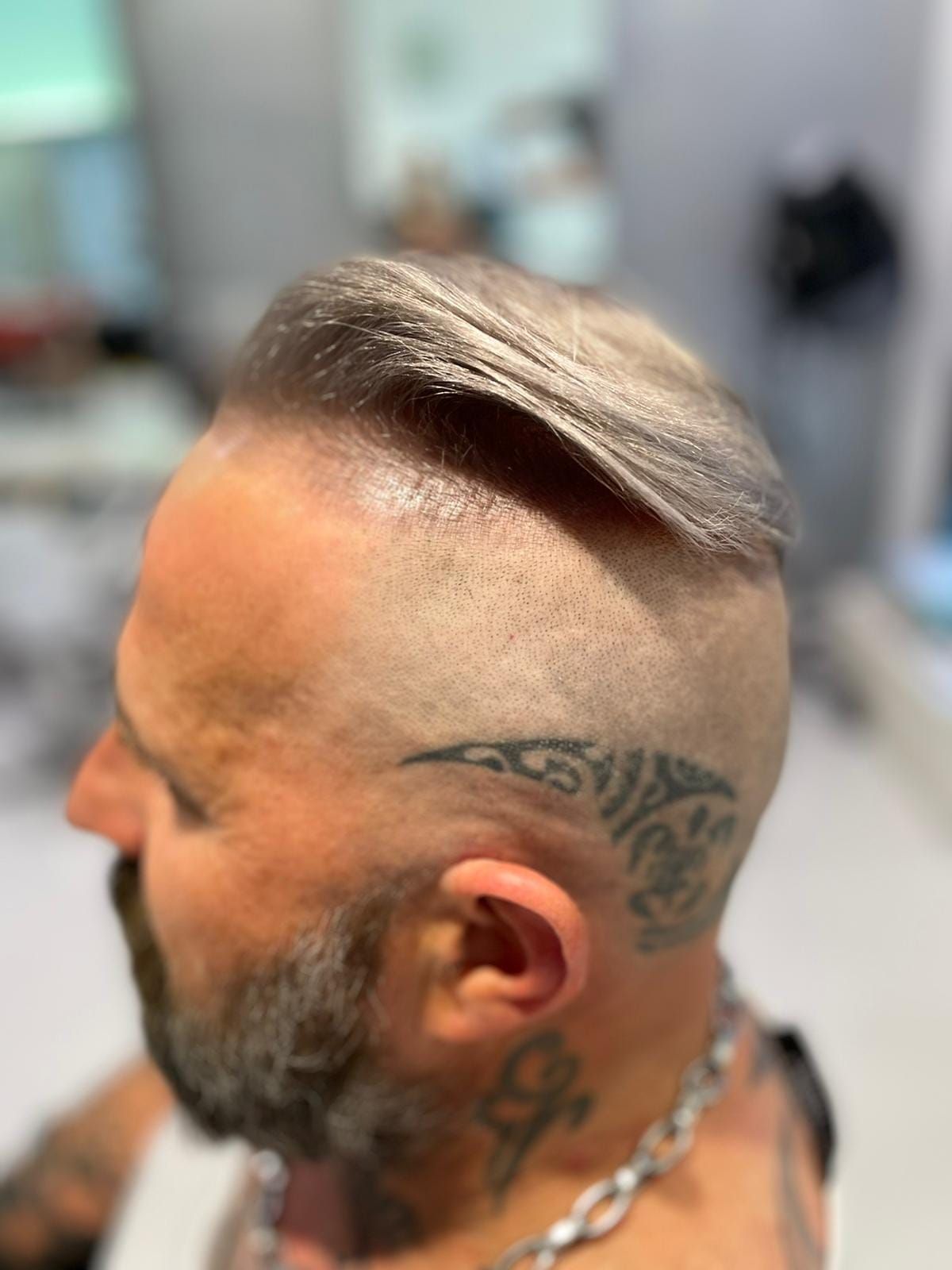 Un uomo con la barba e un tatuaggio sulla testa.