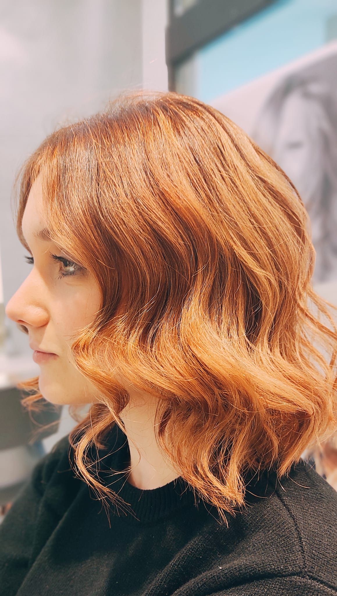 Una donna con i capelli rossi si sta tagliando i capelli in un salone.