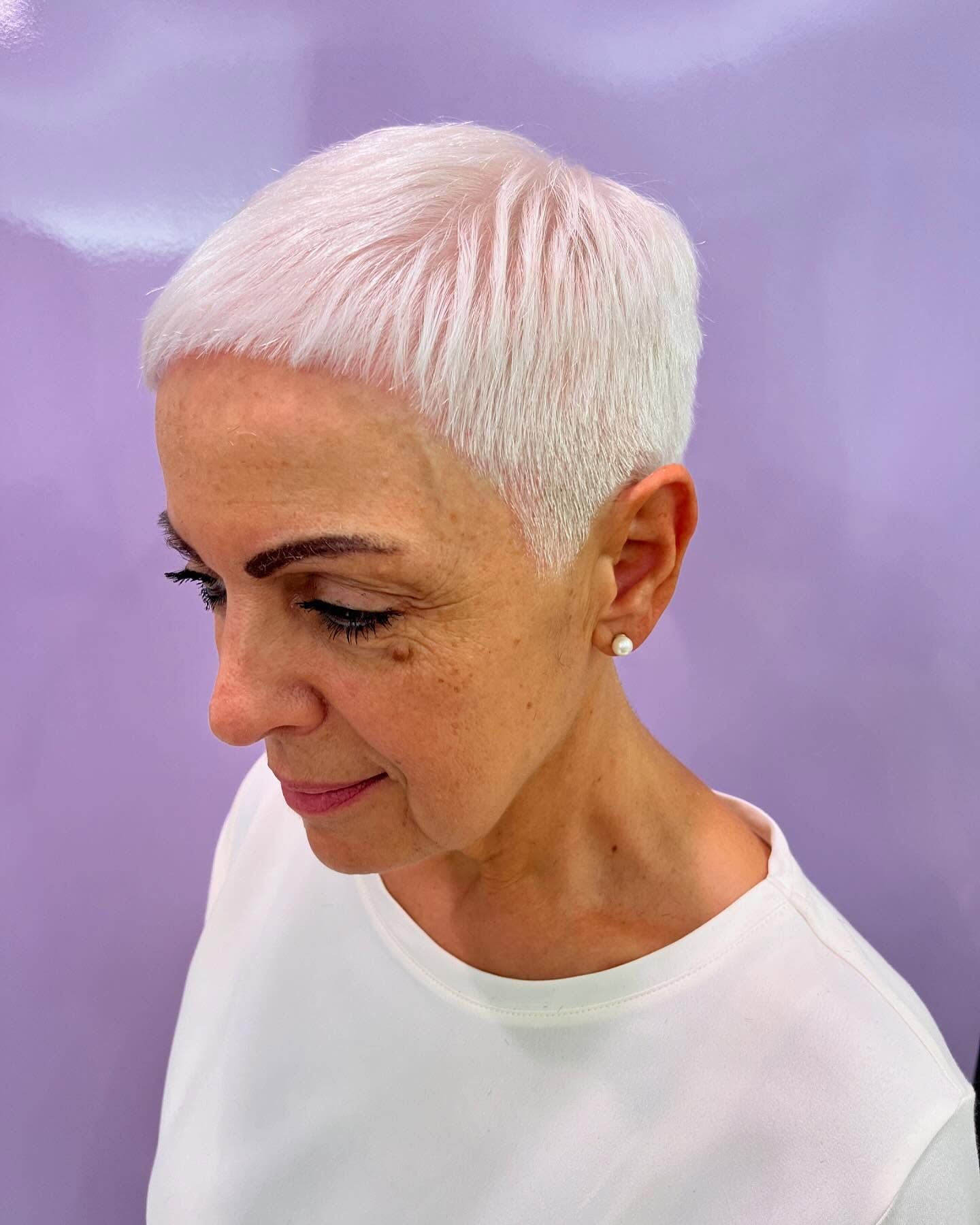 Una donna con i capelli bianchi corti indossa una camicia bianca